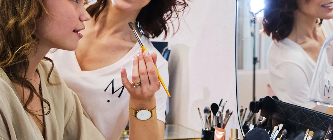 Une esthéticienne conseille une cliente devant un miroir de maquillage
