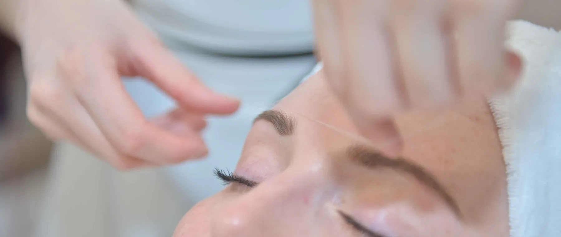 Épilation des sourcils au fil pendant une séance en cabine