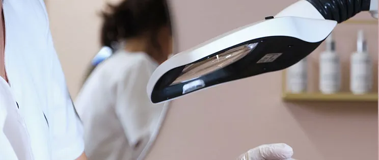 Travail précis sur le visage sous une lampe loupe pendant une séance d’épilation