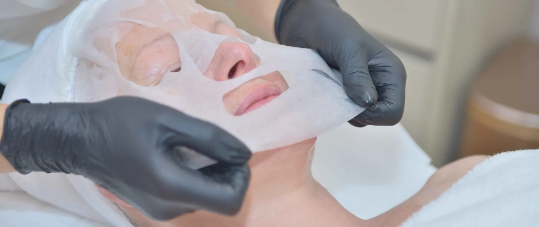Pose d’un masque en tissu sur le visage d’une cliente
