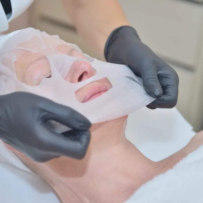 Pose d’un masque en tissu sur le visage d’une cliente