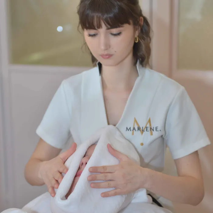 Une esthéticienne applique une serviette sur le visage d’une cliente allongée